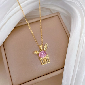 Elegant gold rabbit necklace with pink gemstone and crystals on jewelry box display