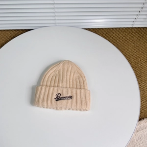 Detail of beige ribbed knit beanie with Pensecolo embroidery on a white decorative plate