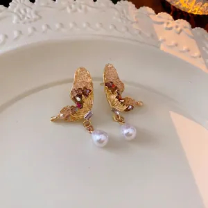 Vintage Schmetterling Ohrringe aus Gold mit Kristallen und Perlenanhänger auf Tablett
