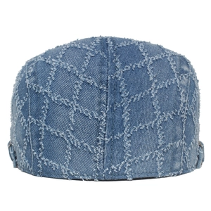 Detailed view of quilted denim beret with frayed edges and washed blue texture