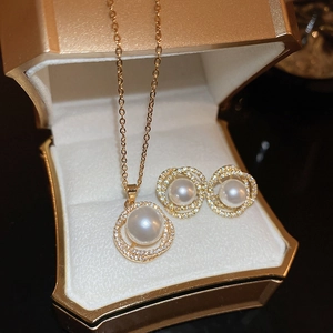Détail d'un ensemble collier et boucles d'oreilles en perles dorées et zircons