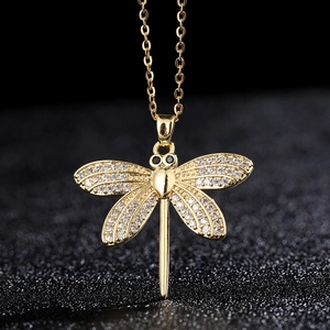 Macro detail of gold-plated dragonfly pendant with pavé cubic zirconia and black gems