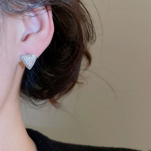 Gros plan d'une boucle d'oreille triangle argentée scintillante avec zircone sur un modèle