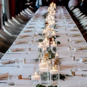 Elegante glazen cilindrische kaarshouders met drijfkaarsen op een romantische tafel