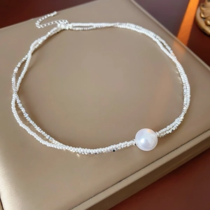Détail d'un collier double couche en perles et billes d'argent sur plateau