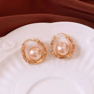 Elegant U-shaped gold earrings with champagne zircons and a central pink pearl inlay
