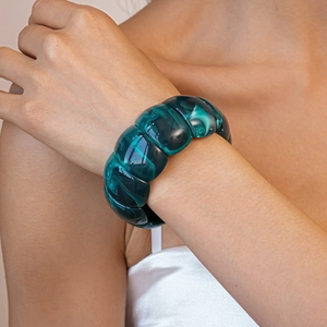 Macro detail of dark teal acrylic geometric bracelet with natural marble texture