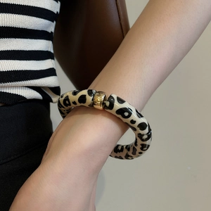 Close-up of leopard print chunky link bracelet with gold metal clasp on model's wrist