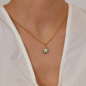 Close-up of golden star necklace with colorful abalone shell and blue evil eye detail
