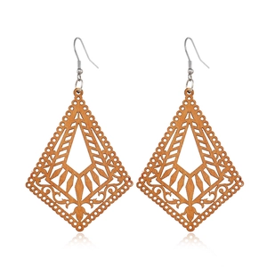 Detail of hollowed-out diamond-shaped wooden earrings with intricate geometric patterns