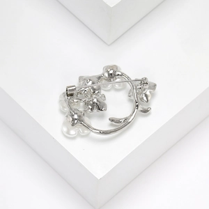 Detail of silver floral wreath brooch with white pearls and back pin on white props