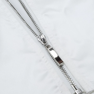 Detail shot of a polished silver metal zipper on premium white woven fabric material
