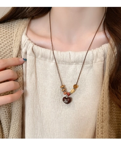 Detail of vintage heart pendant with saturn logo on colorful wooden beaded necklace