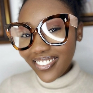 Close-up of tortoise shell oversized cat eye frames with wide beige temples on model