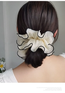 Close-up of oversized cream pleated scrunchie with black trim on a ponytail hair