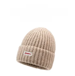 Dettaglio ravvicinato della trama in maglia beige con piccola etichetta tessuta applicata