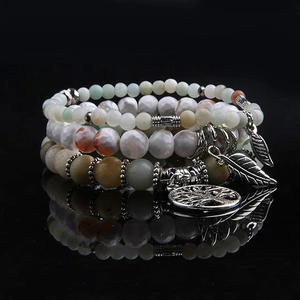Close-up of tree of life and leaf charms on multilayer bohemian turquoise beaded bracelet