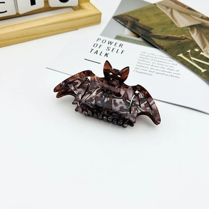 Detail of bat-shaped hair claw clip in dark brown tortoiseshell with glitter accents