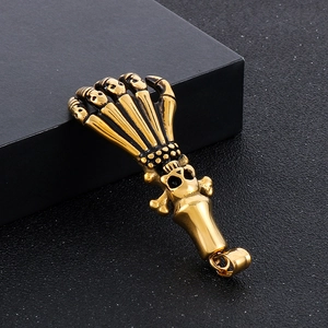 Detailed view of vintage gold-tone skeleton hand clutching a skull pendant in high relief