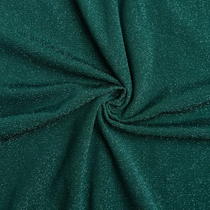 Macro view of dark green glitter fabric texture with shiny sequins and subtle pleats