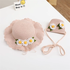 Detail of pink straw sun hat with daisy accents and matching woven bag for girls