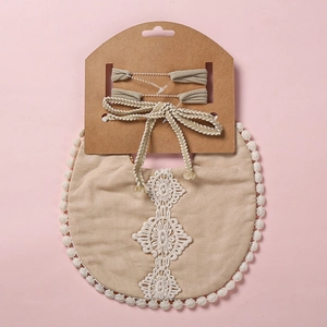 Détail du bavoir bébé beige avec broderie dentelle et bandeaux à nœuds assortis