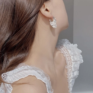 Close-up of S925 silver earring featuring irregular wavy texture on female model