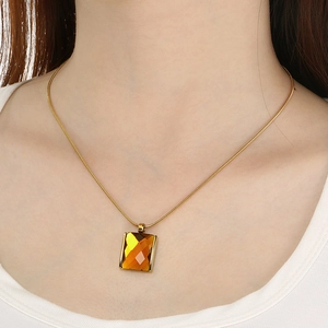 Detail of amber square glass pendant with elegant gold-plated snake chain on woman's neck