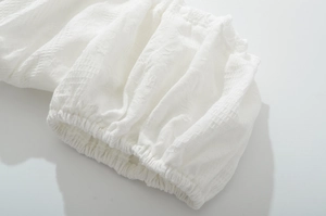 Detailed close-up of white grid-textured fabric with elastic cuff and delicate folds