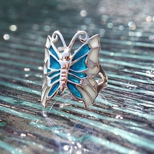 Macro shot of silver butterfly ring with blue and cream enamel inlay and cut-out details