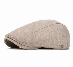 Detail of cream newsboy cap showing wool-like texture and side metal logo plaque