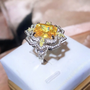 Macro shot of yellow rectangle-cut gemstone ring with diamond pavé in a white gift box