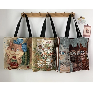 Detailed view of three hanging tapestry tote bags with cartoon cat and floral prints