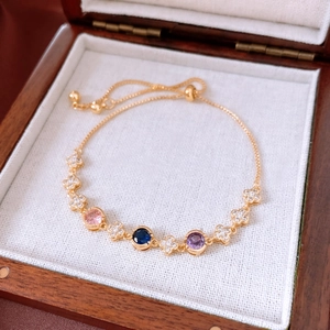 Detail of adjustable 18k gold plated flower bracelet with colorful gems in a jewelry box