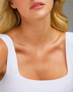 Close-up of a gold stainless steel letter M pendant necklace worn on a female model