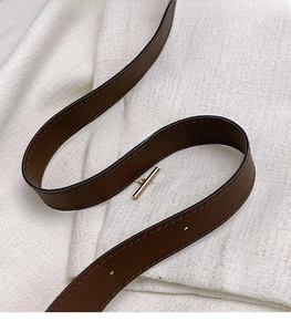 Detail of adjustable dark brown leather shoulder strap with golden buckle and stitching