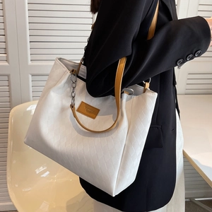 White quilted tote bag with brown leather strap and silver chain shown on model