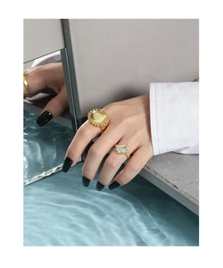 Detail of silver rings featuring gold finish textured foil surface and zircon inlay