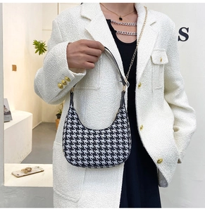 Detail of houndstooth baguette bag with gold chain strap on model in tweed jacket