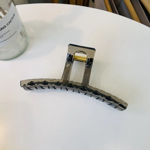 Detailed view of large translucent dark grey hair claw clip with golden metal spring