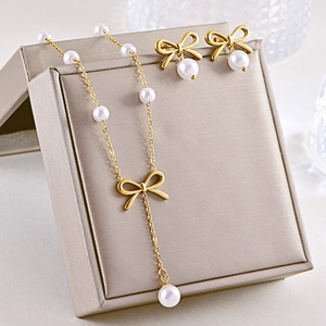 Detail of bowknot pearl necklace and earrings set displayed on a gold jewelry box