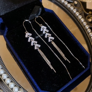 Macro shot of silver tassel earrings with zircon chevron links in a blue velvet box