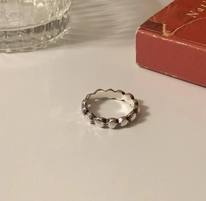 Close-up of a 925 sterling silver ring featuring a geometric faceted texture and wavy edges