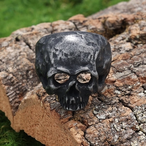 Retro gothic skull ring in oxidized silver steel on a rustic wood bark backdrop