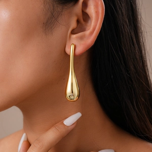 Nahaufnahme des goldenen Tropfenohrrings am Modell mit glattem Metallic-Finish