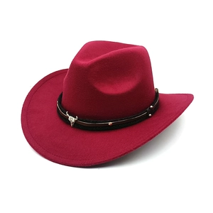 Detail of dark red western cowboy hat with black braided band and silver bull skull buckle