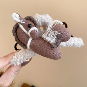 Detail of horse-shaped acrylic hair claw clip with brown fabric and white plush textures