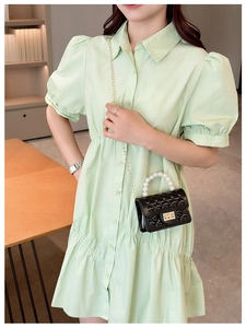 Side view of a black quilted pearl handle bag on a model wearing a green dress
