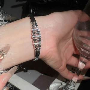 Close-up of silver hollow geometric bangle with zircon inlay on a model wrist