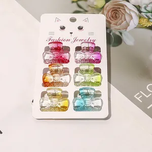 Mini glittery acrylic bow hair claw clips set in vibrant colors on a display card